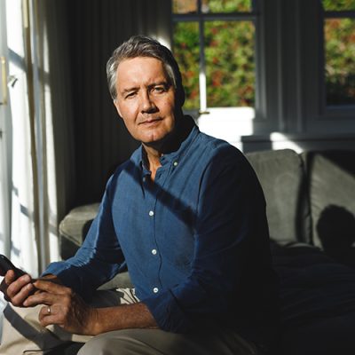 Portrait of happy senior caucasian man in living room sitting on sofa, using smartphone. retirement lifestyle, spending time at home with technology.
